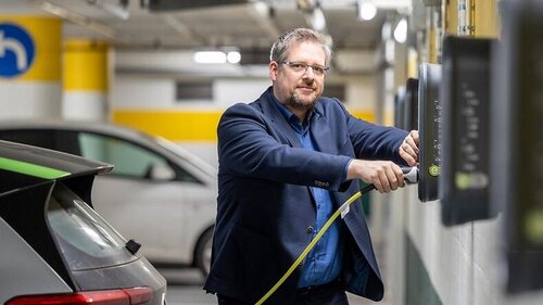 Sascha Hemmen in der Tiefgarage mit E-Stecker in der Hand