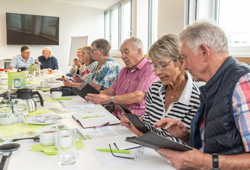 Senioren vertieft in ihre Smartphones während der Smartphone Schulung bei der WOBCOM