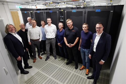 Alle lächeln in die Kamera, während sie in dem neuen Rechenzentrum stehen.