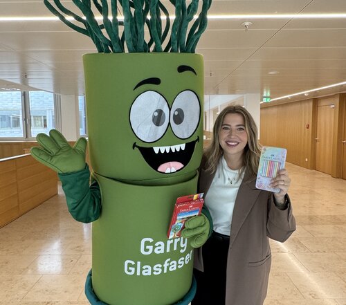 Garry Glasfaser steht mit einer Frau arm in arm. Beide haögten Balstifte in die Kamera.