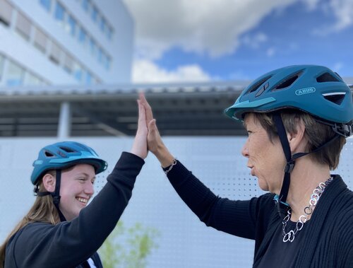 Zwei Frauen mit Fahrradhelmen, die sich abklatschen