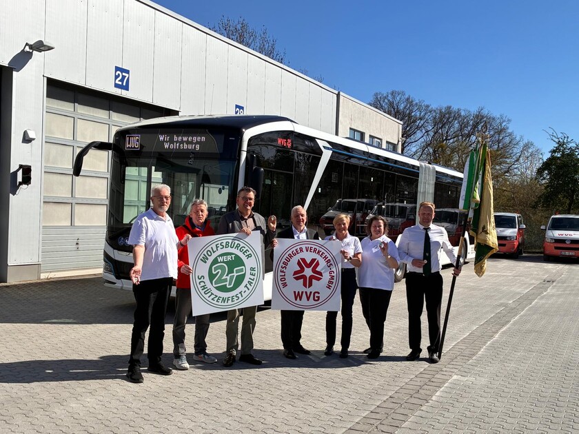 Auf dem WVG-Betriebshof stehen vor einem Bus das Team vom Schützenfest stellt gemeinsam mit der WVG-Geschäftsführung und events38 den neuen Schützenfest-Taler vor.