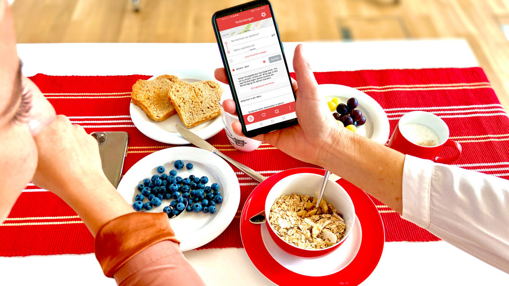 Zwei Personen am Tisch mit Essen und Smartphone mit WVG App
