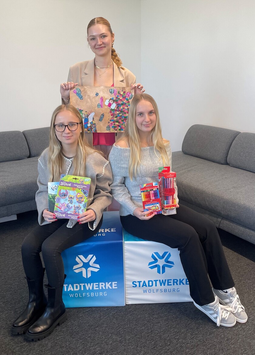 Drei Auszubildende, welche das Cover für das Buch beim Vorlesetag und Bastelsachen in die Kamera halten.