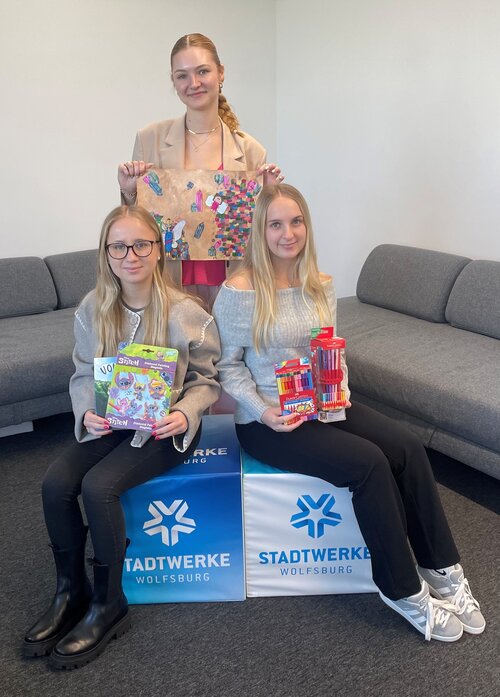 Drei Auszubildende, welche das Cover für das Buch beim Vorlesetag und Bastelsachen in die Kamera halten.