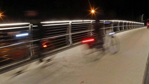 Radfahrende in der Dunkelheit auf einer Brücke