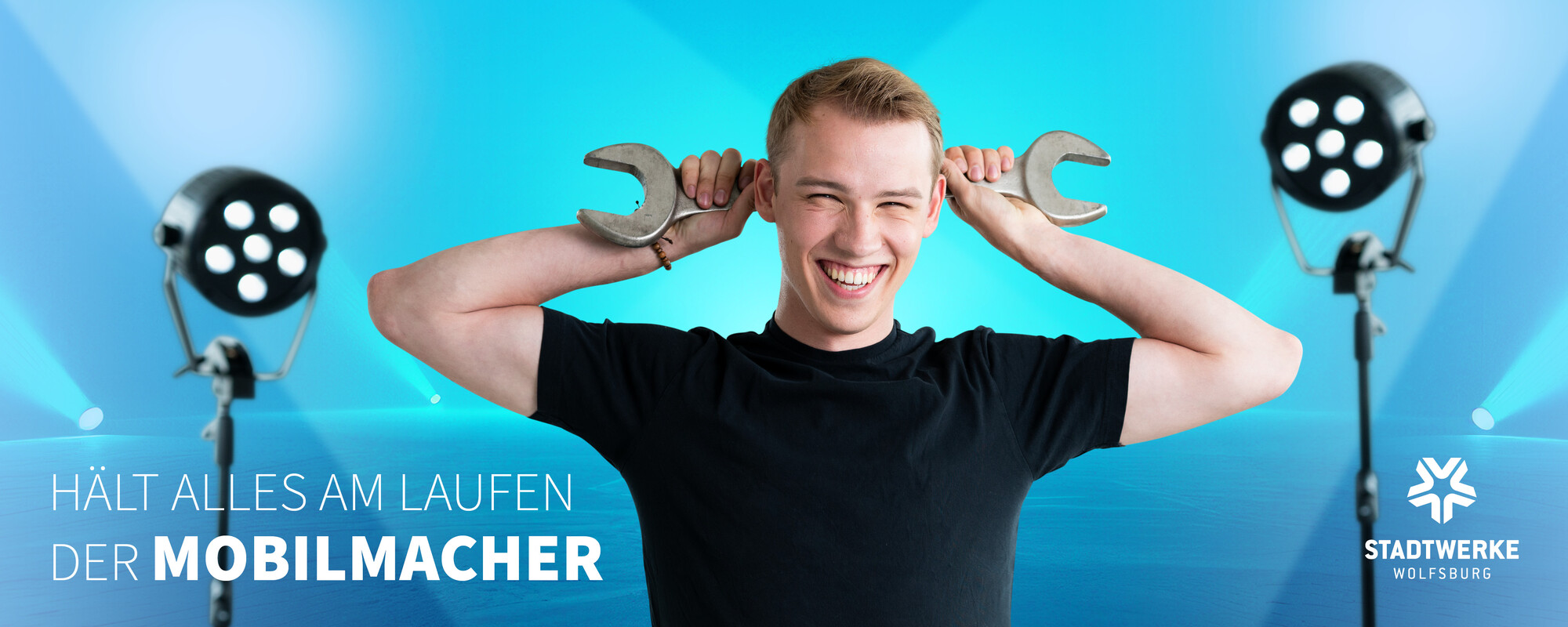 Ein junger Mann hält einen großen Schruabenschlüssel hinter seinem Kopf. Text: Hält alles am laufen - Der Mobilmacher