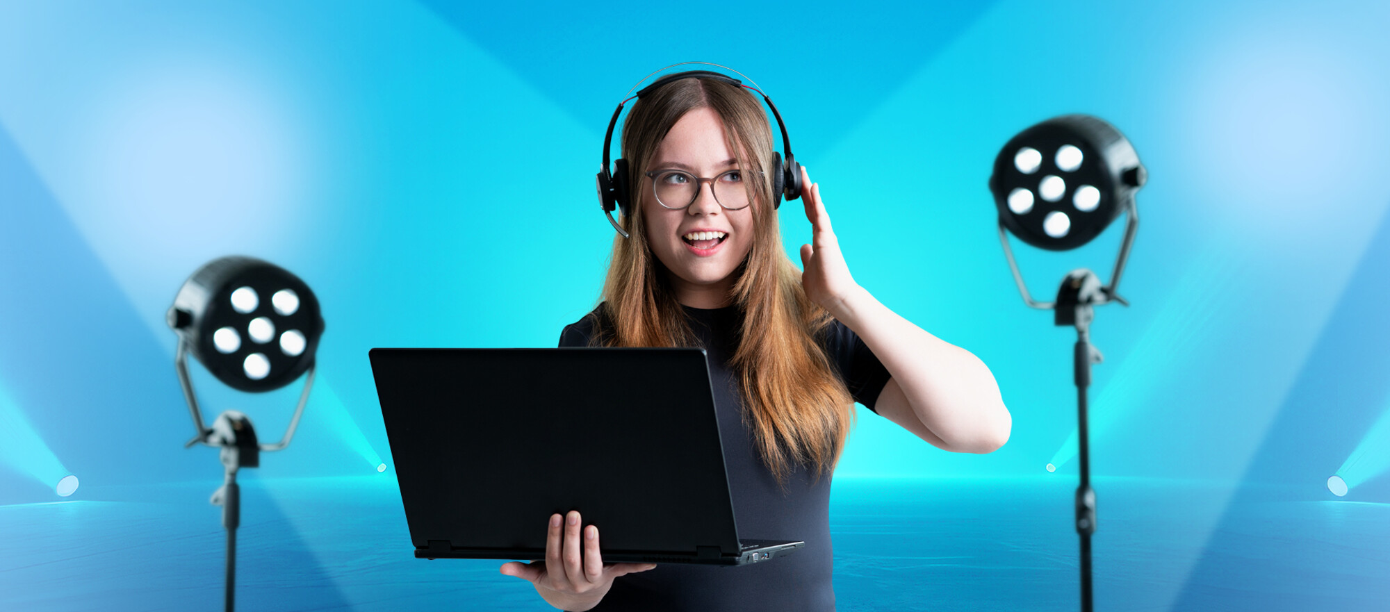 Ein junge Frau mit einem geöffneten Laptop in der linken Hand und Kophörerern auf. 