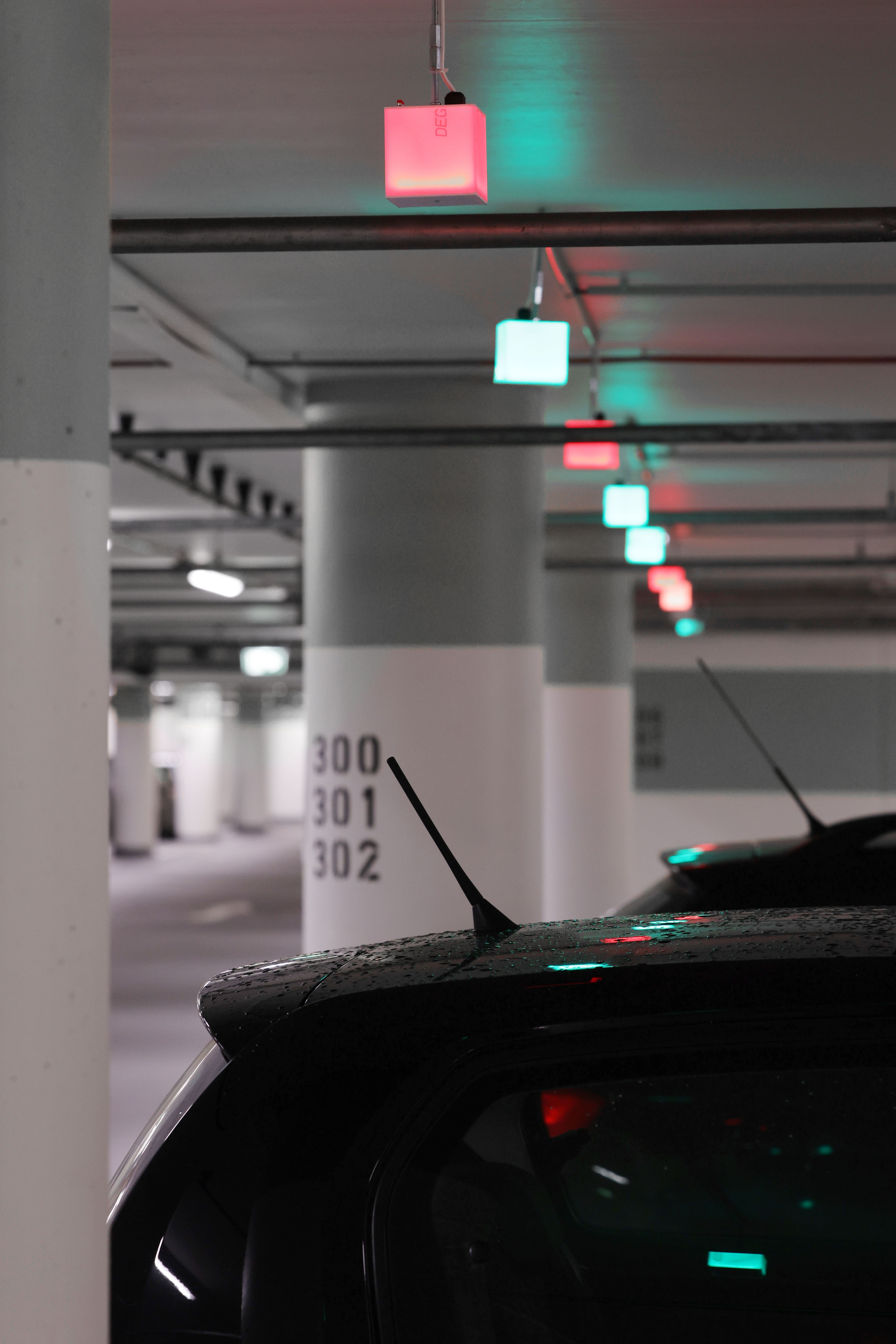 Parkende Autos in einer Tiefgarage, darüber LED-Würfel, den den Parkstatus anzeigen.
