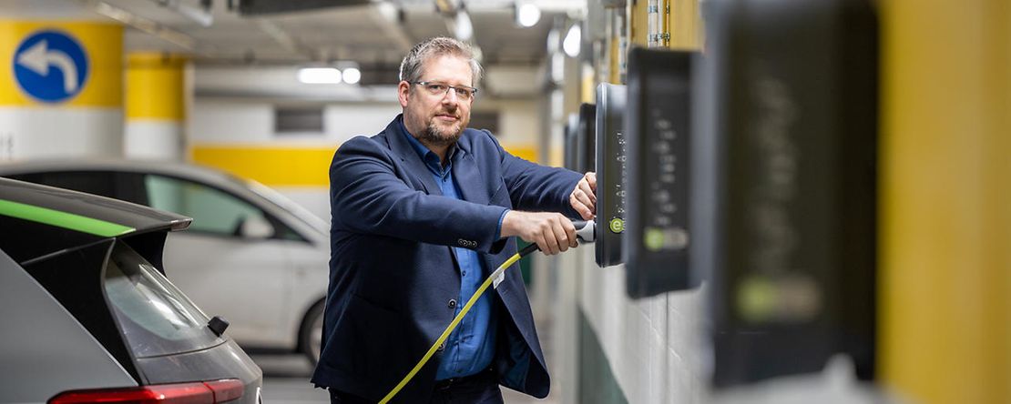 Sascha Hemmen in der Tiefgarage mit E-Stecker in der Hand