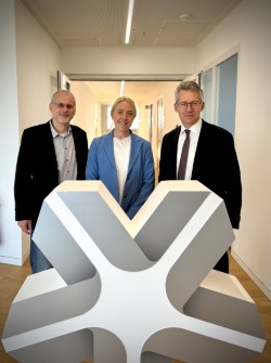 Links auf dem Bild ist der stellvertretende Vorsitzende Oliver Weczerek zu sehen. In der Mitte ist Betriebsratsvorsitzende Sabrina Klinger zu sehen. Rechts auf dem Bild ist Stadtwerke Vorstand Dr. Frank Kästner zu sehen. Sie stehen vor einem großen grauen Stadtwerkelogo Stern.